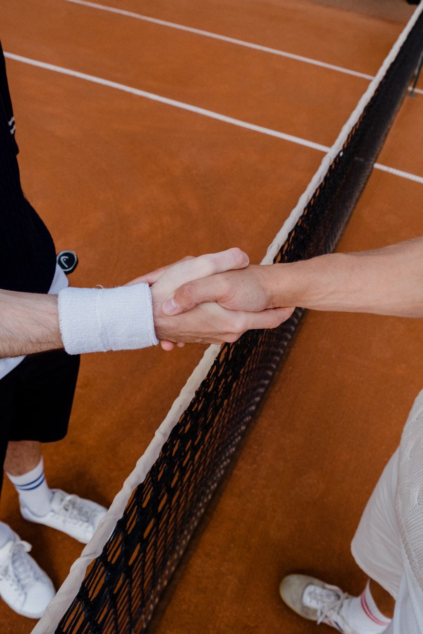 tennis players shaking hands over the court net